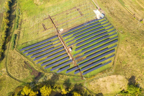 Preview: Aerial view of solar power plant under construction on green field. Assembling of electric panels