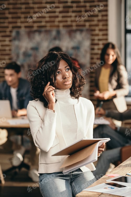 Preview: african american casual businesswoman sitting and talking on smartphone in loft office with