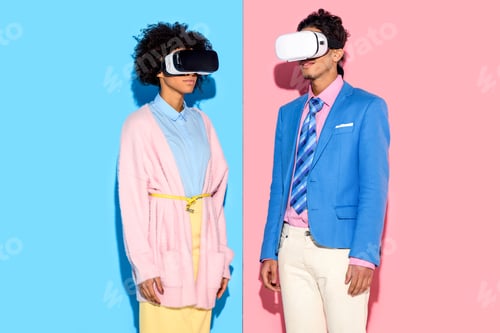 Preview: portrait of african american couple in vr headsets against pink and blue wall background