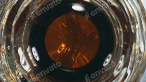 Preview: Dark lager overflowing bottle closeup. Unfiltered cool beverage splashing flask
