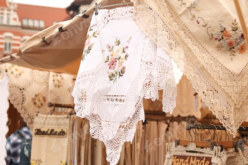 Preview: handmade handkerchief shawl hanging in fair outside. Woven napkins with flowers decorated. Vintage s