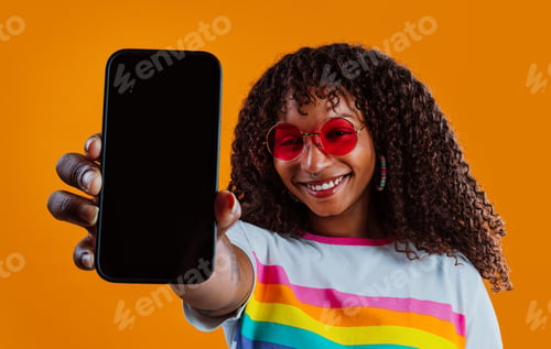 Preview: Young woman showing peace sign with rainbow t-shirt and orange background