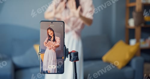 Preview: Asian girl blogger front of phone camera record video enjoy with dance content in living room.