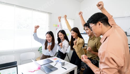 Preview: Group of happy young business people celebrating success together in the office,