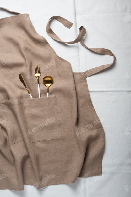 Gold Cutlery with Apron on Neutral Background