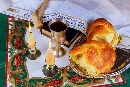 Preview: Shabbat eve table with uncovered challah bread, candles and kippah.