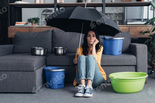 Preview: Pensive brunette girl sitting on floor with umbrella