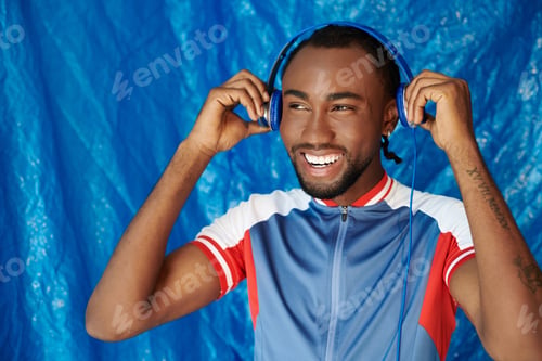 Preview: Joyful young man enjoys music against a vibrant blue backdrop with a cheerful expression