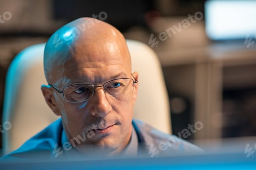 Preview: Experienced businessman in eyeglasses looking at computer screen