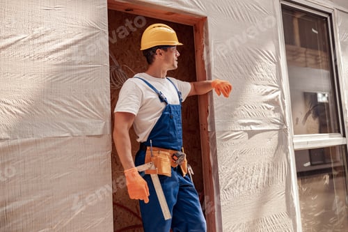 Preview: Handsome man builder standing in doorway at construction site