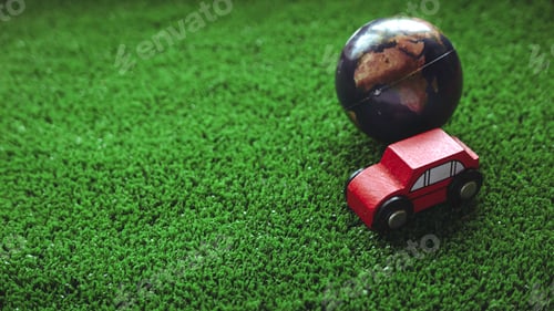 Preview: A toys car and a globe over a green field grass. Eco and environment vehicle concept.