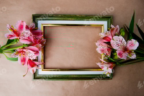 Preview: top view of an empty picture frame with pink color alstroemeria flowers on brown paper texture