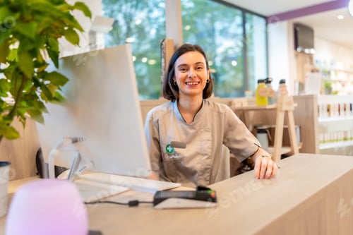 Preview: Cheerful saleswoman working on the counter of a pharmacy store