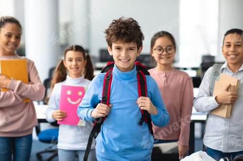 Preview: Smiling international schoolchildren standing and posing at classroom