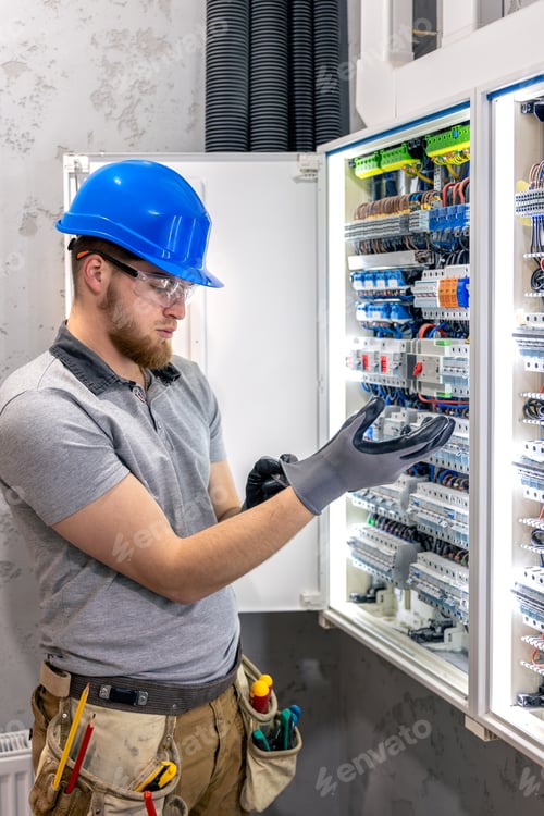 Preview: Male electrician in uniform working in a switchboard. Electricity.
