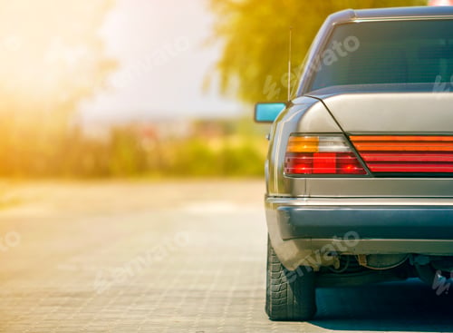 Preview: Back view of silver car parked on paved street in quiet area on sunny bright background