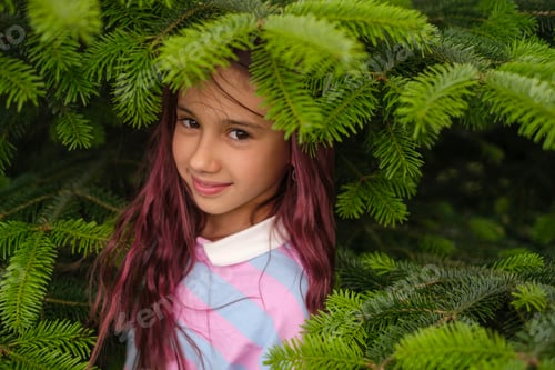 Preview: Portrait of a beautiful sweet girl among the branches of a green fir tree