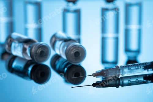 Preview: Closeup shot of covid19 vaccine bottles with a needle on a blue background - covid19 concept