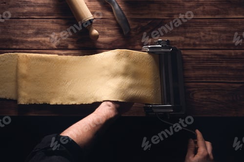 Preview: Top view of a person rolling the dough using a dough roller sheeter