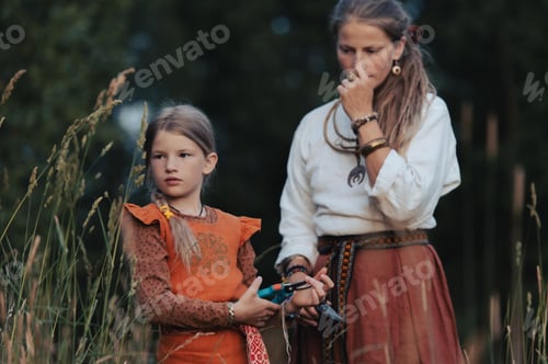 Preview: Midsummer celebration countryside- mom and girl wearing national costumes collect medicinal plants