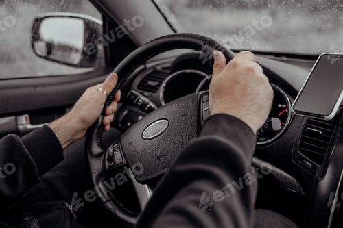 Preview: Male hands on black steering wheel of modern car. Automobile saloon. Driving on road concept.