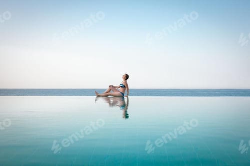 Preview: Woman Relaxing by Infinite Swimming Pool
