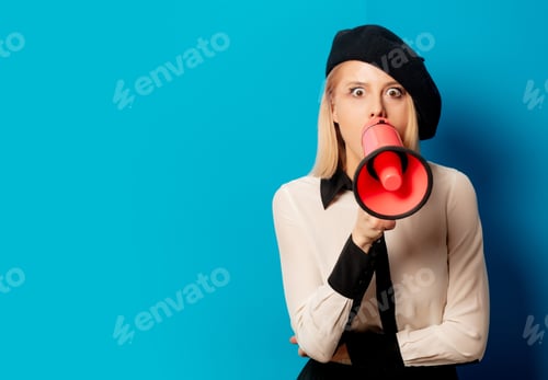 Preview: beautiful french woman in beret holds loud-hailer on blue background