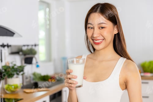 Preview: Young Asian Thai woman holding glass of milk and drinking