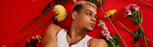 Preview: Young man showcases trendy style with dyed hair in vibrant red studio setting