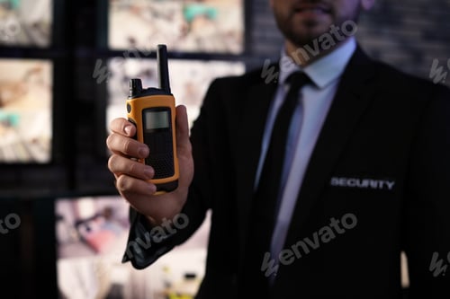 Preview: Male security guard with portable transmitter near cameras indoors, closeup