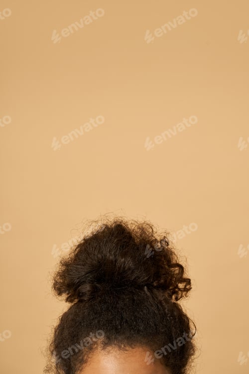 Preview: Studio shot of young mixed race woman with highly raised dark curly hair posing isolated over beige