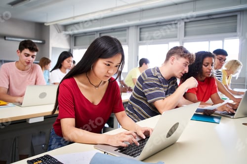 Preview: A young Asian high school student studies using a laptop computer. A group of classmates in class.