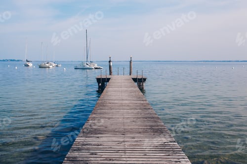 Preview: View of a wooden pier on the seashore with clear morning sky and sea with turquoise water.