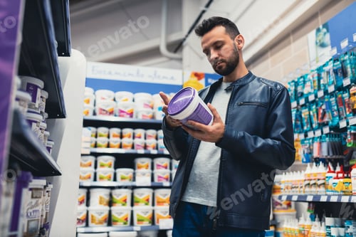 Preview: a man in a construction hypermarket chooses paint for repairs in the house
