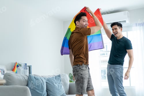 Preview: Asian handsome man gay family holding LGBTQ flag and dance together.