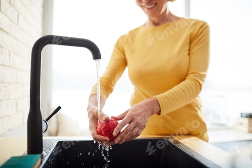 Woman Washing Red Apple at Kitchen Sink