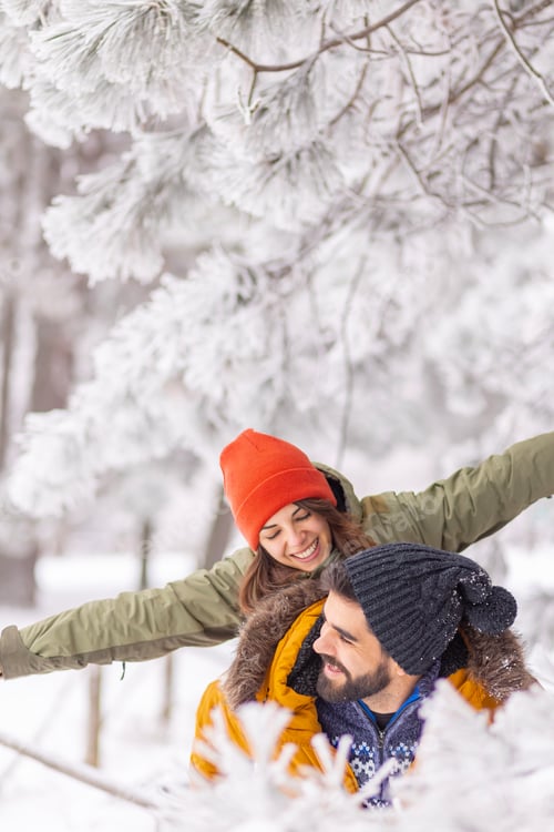 Preview: Man piggybacking woman on snowy winter day outdoors