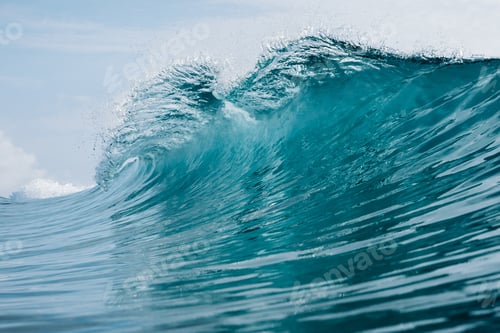 Preview: Turquoise ocean wave breaking under blue sky, crashing barrel wave
