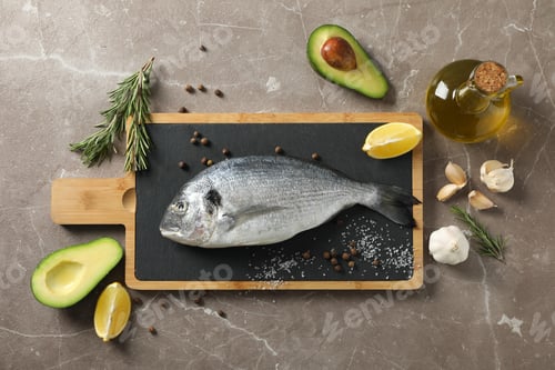 Preview: Cutting board with Dorado fish and cooking ingredients on grey background, top view