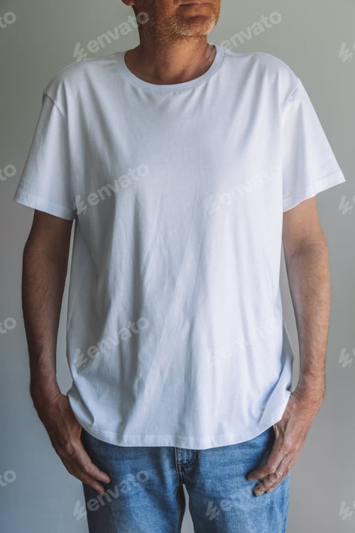 Preview: An unshaven man in an empty white T-shirt and jeans on a gray background. Front view. Mock up design