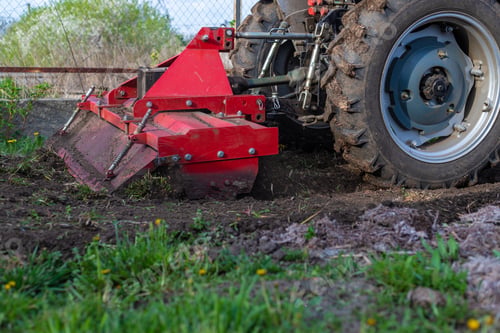 Preview: Tractor cultivating soil in the garden. Selective focus.