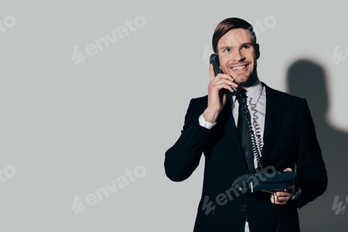 Preview: Young smiling businessman in suit talking on the phone on white background