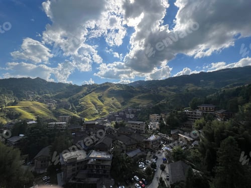 Preview: Stunning aerial shot depicts a vibrant town nestled in a green valley surrounded by mountain
