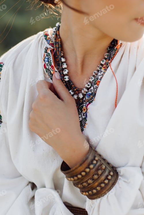 Preview: Young woman in traditional national embroidered shirt and skirt on nature at sunset.