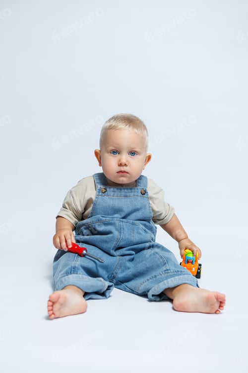 Preview: A cheerful toddler plays joyfully with colorful toys while wearing cute overalls