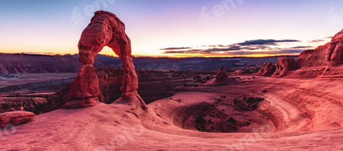 Preview: a stone arch in the desert with mountains and blue sky