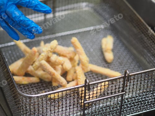 Preview: chef deep fying in boiling oil potato chips and snacks in hotle kitchen