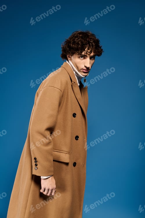 Preview: Young man showcases stylish fashion in a modern setting against a vivid blue backdrop