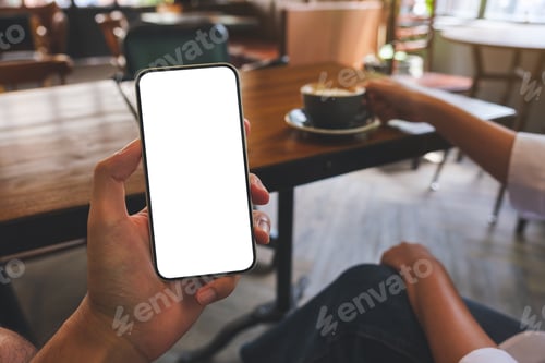 Preview: Mockup image of a man holding black mobile phone with blank white screen in cafe