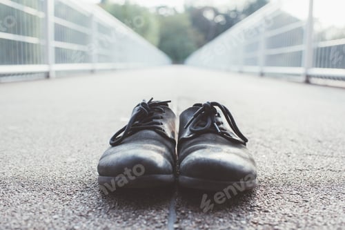 Preview: A pair of lost abandoned shoes on the street pavement.